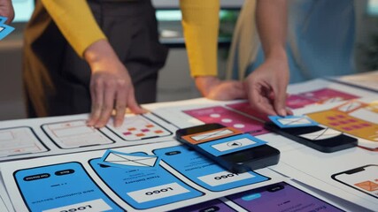 Wall Mural - ui and ux designers are moving and arranging smartphone mockups on a table, developing a mobile appl