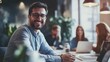© Oulaphone - A smiling man in a modern office setting engages with colleagues, embodying a positive and collaborative work atmosphere.
