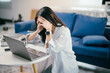 © Parichat - Young asian woman is experiencing stress and burnout while working from her home office. She is holding her head in her hands, feeling overwhelmed by the demands of her work