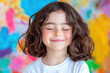 © Nattapol - joyful child with dark curly hair smiles with closed lips, radiating happiness against colorful abstract background. vibrant colors enhance cheerful atmosphere