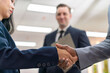 © StockPhotoRepublic - Close-Up of Business Handshake Between Diverse Professionals with Colleague in Background