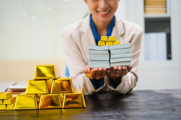 An Asian businesswoman is sitting at her desk, discussing gold bars, deposits,and the gold market with investors.She analyzes gold price trends highlights the long-term benefits of investing in gold