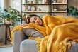 © Aleksandr - Young Woman Resting On Couch Under Warm Blanket, Seeking Comfort And Relief From Illness