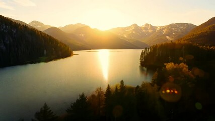 Wall Mural - Aerial footage of a tranquil lake in the forest, with a mountain range in the background at sunset