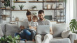 © SS Digital - Happy family spend time in spacious room at home. Couple with child watch online movie on laptop sitting on sofa in cozy light living place space with white grey walls, shelves, hou