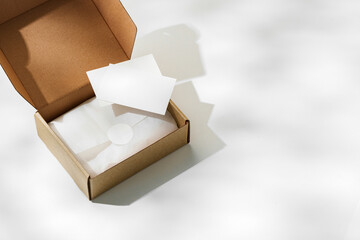 Brown cardboard box with a blank envelope on a light background in a well-lit setting