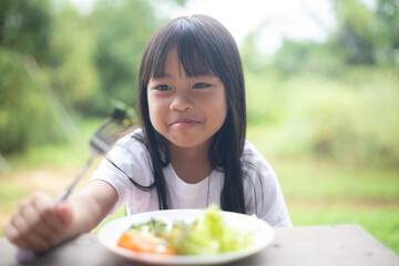 A young girl is eating a plate of vegetables