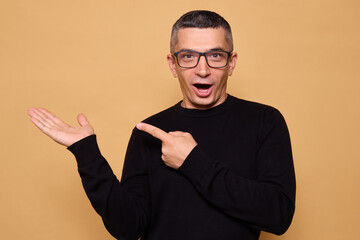 surprised caucasian man wearing black jumper and glasses raising hands in amazement pointing finger 