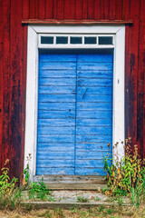 Poster - Blue door on an old red wooden cottage