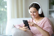 © Antonioguillem - Happy woman listening audio with headphone and cell phone at home