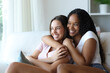 © Antonioguillem - Happy lesbian couple hugging sitting on a couch at home