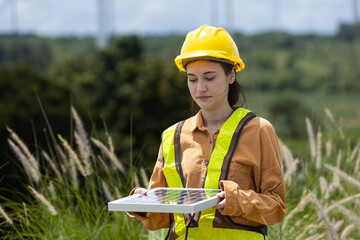 Fototapete - Female engineer ecology solar panel plant environment electricity. Alternative innovation energy. woman holding solar panel wind turbines in background.