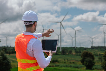 Fototapete - Engineer wearing safety uniform holding laptop discussed plan about renewable energy at station energy power wind. technology protect environment reduce global warming problems.