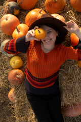 Wall Mural - Woman lying on hay with pumpkins during autumn