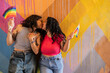 © Westend61 - Affectionate lesbian couple holding pride flag and kissing near painted wall