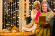 © G-images - Happy senior husband giving surprise gift to excited wife in illuminated home on occasion of Diwali festival