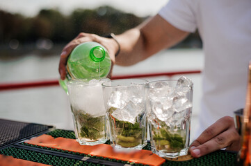 Wall Mural - Refreshing Summer Mojito Preparation with Sparkling Water and Fresh Ingredients