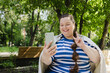 © Westend61 - Happy woman video calling using smart phone and gesturing peace sign at park
