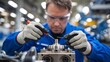 © Deedyy - A factory worker wearing protective gloves, closely examining a machine component with precision tools. The background shows blurred industrial equipment