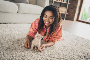 Photo of cute adorable girl dressed orange shirt smiling enjoying her little friend lying foor indoors house apartment room