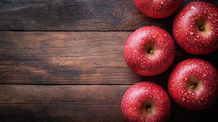 Bright red apples with water droplets on a wooden background, creating a fresh, inviting scene with room for text