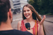 © deagreez - Photo of charming girl giving interview to journalist speaking in microphone broadcast outdoors