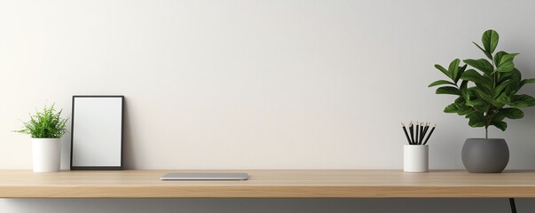 A minimalist desk setup featuring plants, a blank frame, and stationary, ideal for modern workspace aesthetics.