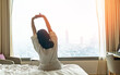 © Chinnapong - Hotel relaxation on lazy day with Asian woman take it easy, waking up from good sleep in weekend morning resting in comfort bedroom with city view having happy work-life quality balance lifestyle