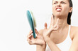 © SHOTPRIME STUDIO - Hair care, brush, frustration, beauty, wellness A woman with a distressed expression holding a hairbrush, showing concern about hair loss against a clean white background, emphasizes hair care