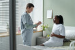 © pressmaster - Medical professional conversing with expectant mother in hospital setting while making notes on clipboard, both focused on conversation in a clean and calm environment