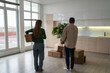 © DimaBerlin - Family with carton boxes stand together in new house after relocation. Couple discusses how to design, furnish new space, considering mortgage, future investment, housewarming for young family