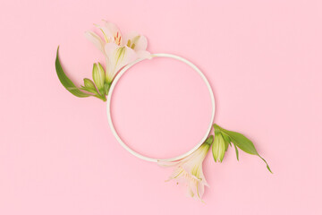 Wall Mural - round frame made of green leaves and white alstroemeria flowers on a pink background.