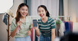 © Johnstocker - Portrait of Two cheerful woman influencers are live streaming to promote a clothing sell during a flash sale on social media or blog in a home studio. Remote shopping, online shopping.