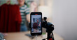 © Johnstocker - Selective focus on mobile phone of Cheerful woman influencer is live streaming sell clothes on social media or blogging in home studio. Remote buying, Online shopping, Sell ​​products online