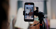 © Johnstocker - Selective focus on mobile phone of Cheerful woman influencer is live streaming sell clothes on social media or blogging in home studio. Remote buying, Online shopping, Sell ​​products online