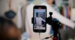 © Johnstocker - Selective focus on mobile phone of Cheerful woman influencer is live streaming sell clothes on social media or blogging in home studio. Remote buying, Online shopping, Sell ​​products online