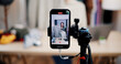 © Johnstocker - Selective focus on mobile phone of Cheerful woman influencer is live streaming sell clothes on social media or blogging in home studio. Remote buying, Online shopping, Sell ​​products online