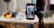 © Johnstocker - Selective focus on mobile phone of Cheerful woman influencer is live streaming sell clothes on social media or blogging in home studio. Remote buying, Online shopping, Sell ​​products online
