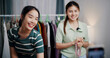 © Johnstocker - Selective focus, Two cheerful woman influencers are live streaming sell clothes on social media or blogging in home studio. Remote buying, Online shopping, Sell ​​products online