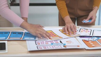 Wall Mural - two designers are working on a user interface for a mobile phone application. they are placing diffe