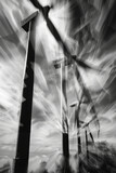 Windmills spin in wind at wind farm, creating dynamic and powerful scene. dramatic black and white filter enhances movement and energy of turbines