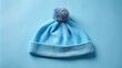 © Autun - Soft blue cotton sleeping cap adorned with a fluffy pom at the top, resting against a gentle light blue background.