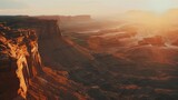 A breathtaking aerial view of a sunlit canyon with layers of rock formations stretching into the horizon, bathed in golden light.