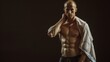 © VK Studio - A muscular man with a shaved head holds a towel over his shoulder against a dark background, showcasing his physique.