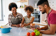 © NDABCREATIVITY - Happy black family in the kitchen having fun and cooking together. Healthy food at home.