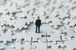 © dony - Business solutions, success and strategy concept. Miniature people: small businessman standing on white jigsaw puzzle