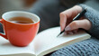 © Worakit - person journaling with cup of tea by their side, creating cozy and reflective atmosphere. warm drink complements thoughtful writing experience