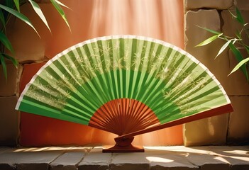 A green and white folding fan with a bamboo frame and a tassel