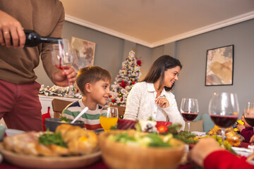 Man pouring wine for family Christmas dinner