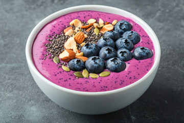 Vibrant berry smoothie bowl topped with fresh blueberries, almonds, chia seeds, and pumpkin seeds for a nutritious breakfast or snack option.